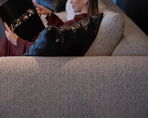 A person resting and reading a book on a comfortable sofa