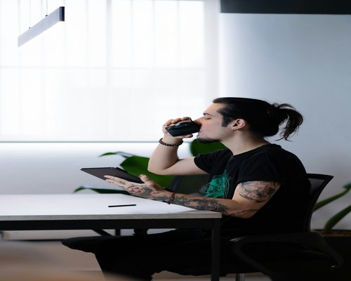 Person working at a modern office desk taking a sip from a glass of water